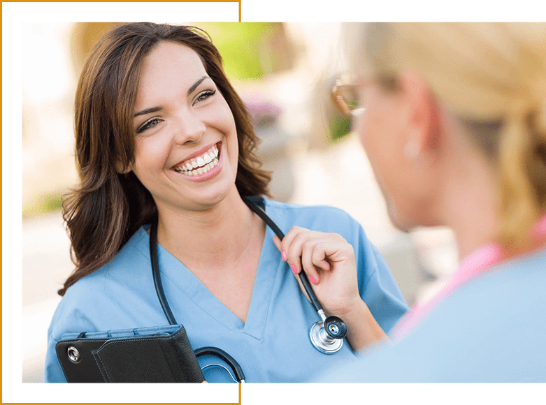 A woman in scrubs is holding her stethoscope